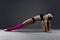 Muscular attractive fitness woman warming up in the studio on gray background