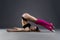 Muscular attractive fitness woman warming up in the studio on gray background