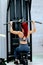 Muscular attractive sporty woman using training simulator for pumping back muscles. Training concept, strong woman