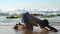 Muscular bearded man does yoga stretching in shallow water