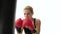 Muscular blond girl boxer with cries kicking punching bag