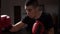 Muscular boxer throwing punches in the boxing bag in a darken sport gym in slow motion -