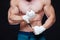 Muscular Fighter kickbox With white Bandages against the black background.