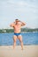 Muscular fit guy on sandy river beach. Strong athlete relax on a summer day.