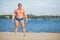 Muscular fit guy on sandy river beach. Strong athlete relax on a summer day.