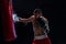 Muscular handsome boxer giving a forceful forward kick during a practise round with a boxing bag.