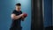 Muscular handsome fighter giving a forceful forward kick during a practise round with a boxing bag, kickboxing. Close up