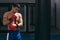 Muscular hardworking fighter practicing with punching bag indoor.