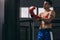 Muscular hardworking fighter practicing with punching bag indoor.