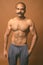 Muscular Indian man with mustache shirtless against brown background