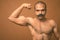 Muscular Indian man with mustache shirtless against brown background