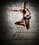 Muscular jumping woman on brick wall (dark version)