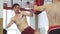 Muscular kick boxer working out shirtless doing high kicks on kicking pads