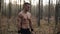 Muscular Male Athletic With Naked Torso Stands In The autumn forest. leaves fall from trees. Slow motion.