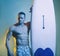 Muscular male body on blue background. Sexy surfer surfing man with surfboard.