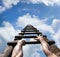 Muscular male hands gripping wooden ladder and reaching to the top, to the blue sky with white clouds and light