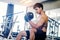 Muscular Man built athlete working out in gym sitting on weightlifting machine and lifting dumbbel