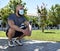 Muscular man crouched down in a public park wearing a face mask, with a lot of space on the right side