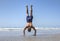 Muscular man doing handstand on beach