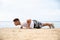 Muscular man doing push up on beach. Body training