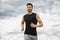 Muscular man jogging outdoors, dramatic sky backdrop