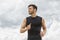 Muscular man jogging outdoors, dramatic sky backdrop