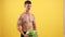 muscular man lifting heavy water melon for biceps muscles on yellow background, sport