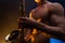 Muscular man naked torso playing on saxophone with smoked colorful background