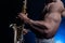 Muscular man naked torso playing on saxophone with smoked colorful background