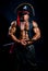 Muscular man in a pirate costume with a sword on a black background