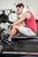 Muscular man on rowing machine wiping sweat with towel