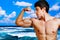Muscular man showing his biceps on the beach