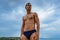 Muscular man standing on the beach in a speedo. The concept of freedom, power, sport, healthy lifestyle.