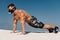 Muscular man workout doing push-ups exercises outdoors. Strong male naked torso abs on the beach