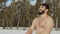 Muscular naked sportsman tempers the body with snow at forest background