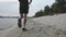 Muscular powerful male legs runs along river beach.  Follow view of slim male legs jogging near river in evening. Young fit boy tr