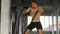 Muscular powerful young man training with battle rope doing exercise in functional training fitness gym