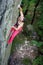 Muscular rock climber climbs on cliff wall with rope