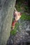 Muscular rock climber climbs on overhanging cliff