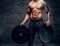 The muscular shirtless, tattooed male holds barbell weights over
