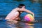 Muscular sport boy swimming in lake with ball
