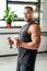 Muscular sportsman posing with dumbells in custom gym