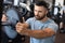 Muscular sporty indian man adding weight on barbell at gym