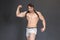 Muscular strong athletic bodybuilder or fitness model showing muscles by two hands and posing near grey wall. Concept sport photo
