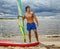 Muscular surfer posing with surfboard.