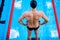 Muscular swimmer preparing to jump from starting block in a swimming pool