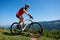 Muscular tourist cyclist in helmet, sunglasses and full equipment riding bike on grassy hill