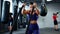 Muscular woman doing battle rope exercise in cross training gym.