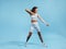 Muscular woman exercising with elastic band. Female in fitnesswear pulling resistance band on blue background