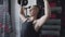 Muscular woman sits on bench and lifts dumbbells up at gym